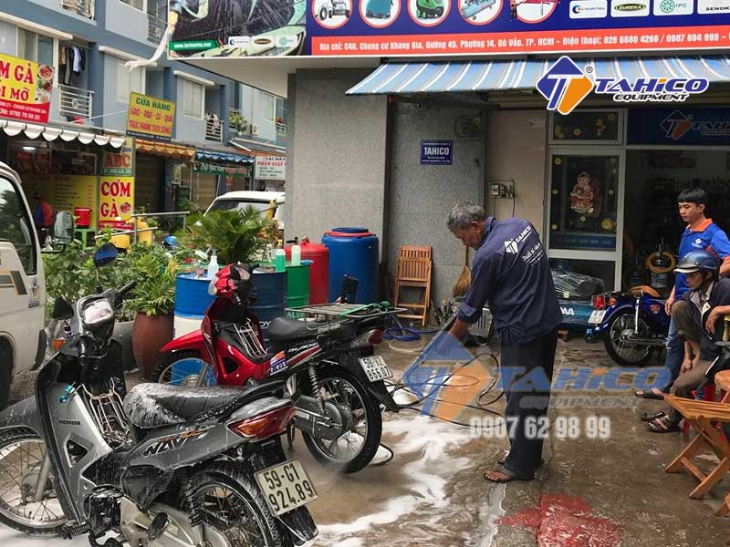 Nhân viên giao hàng dùng máy rửa xe cao áp để rửa xe máy
